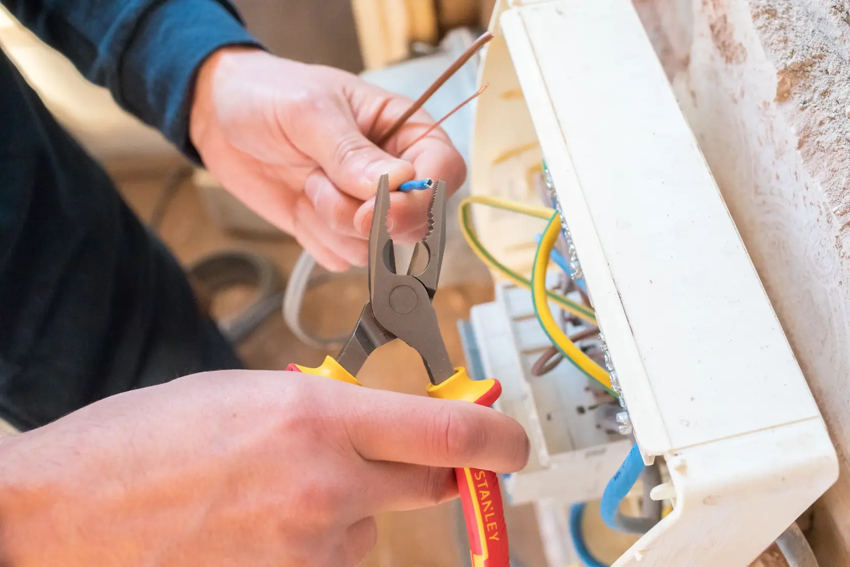 STANLEY 0-84-000 pliers being used to strip wire near an electrical panel.