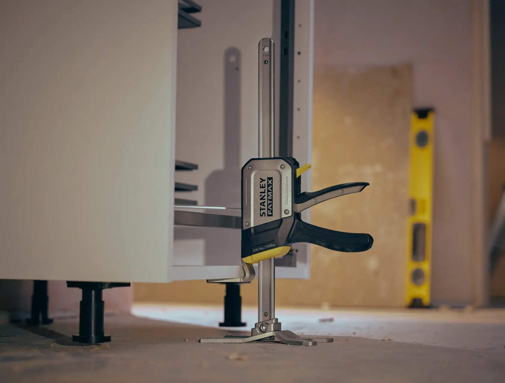 STANLEY FMHT83550-1 clamp securing cabinet, photography from side angle on workshop floor.