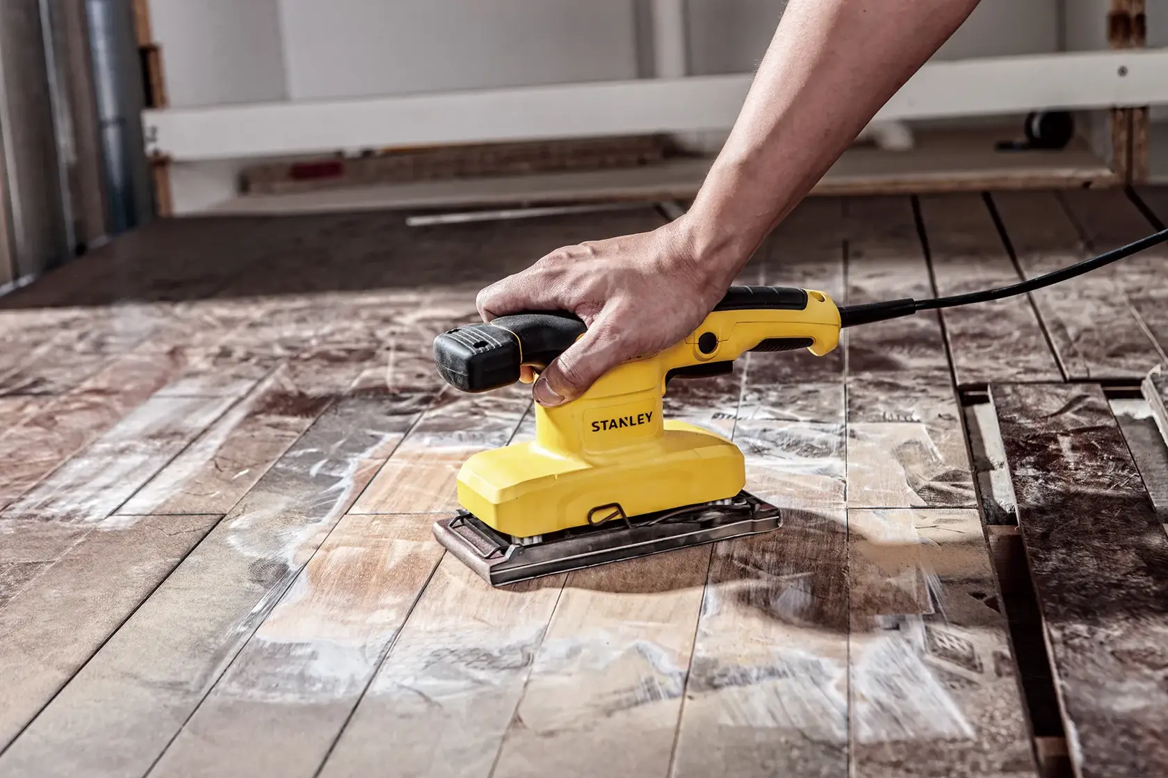 STANLEY SS28-AR sheet sander in use on wooden floor, side angle, yellow and black design.