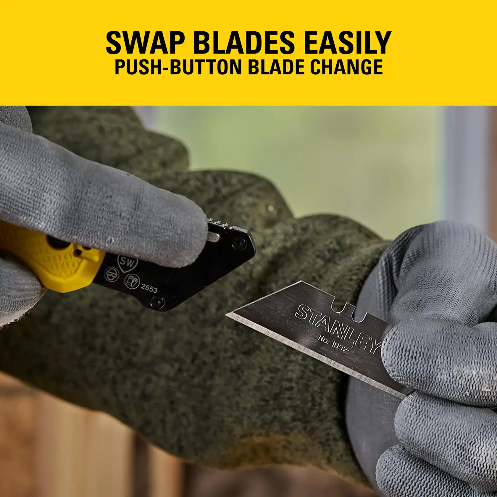 Gloved hands swapping STANLEY utility knife blade with easy push-button change feature.