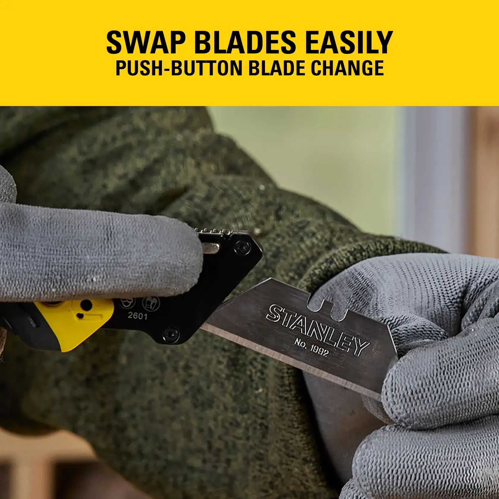 Gloved hands swapping STANLEY utility knife blade using push-button mechanism, close-up view.