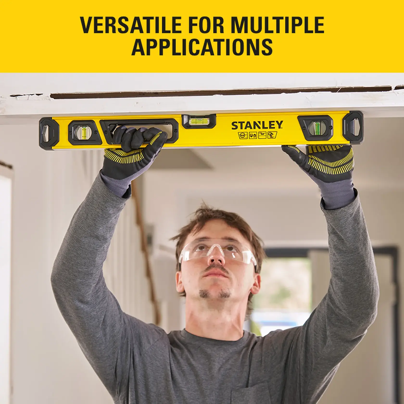 Person using STANLEY STHT41024-0 yellow spirit level for leveling a door frame indoors.