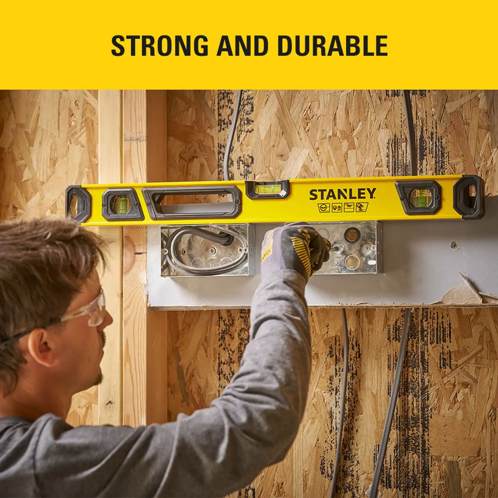 STANLEY STHT41024-0 spirit level used on electrical box during wall installation, horizontal view.