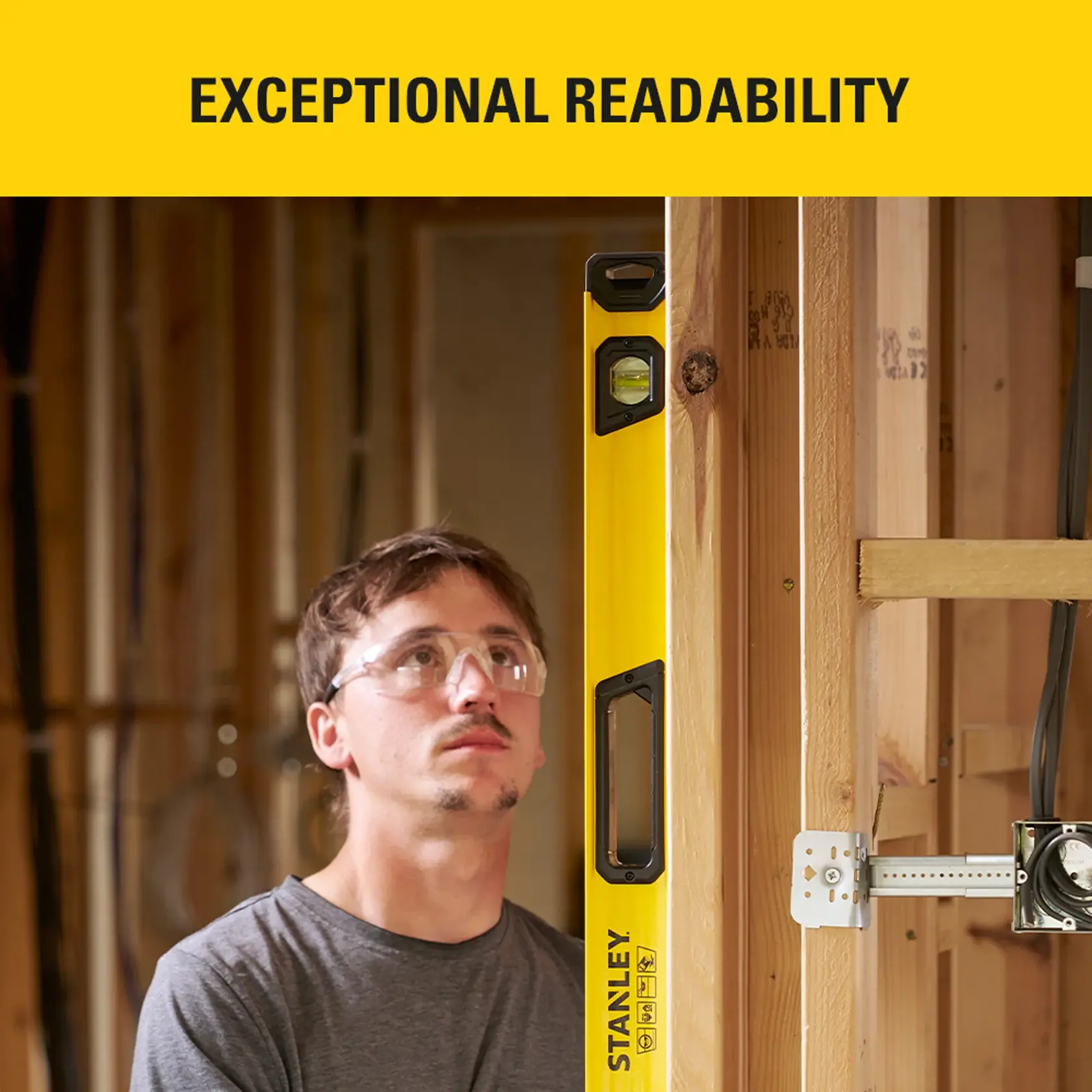 Photo of man using STANLEY STHT41048-0 level tool on wooden wall frame during construction, front angle.
