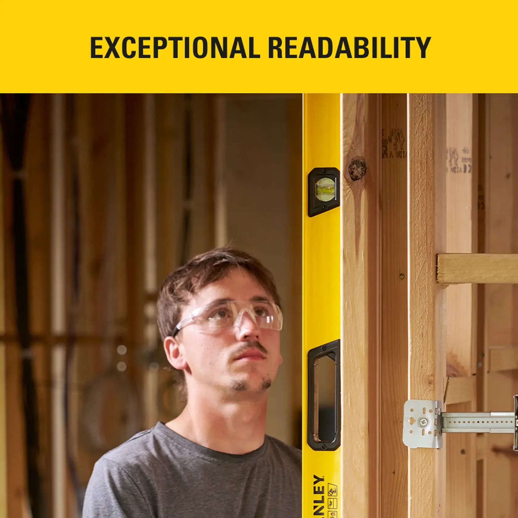 Stanley STHT41072-0 spirit level in use on wooden frame at construction site, shown upright beside worker.