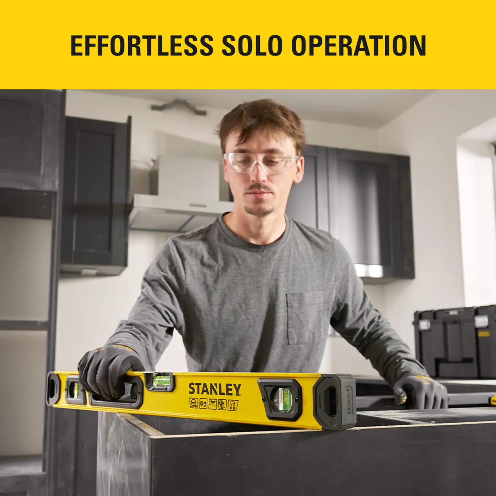 Photo of worker using STANLEY STHT41724-0 level tool on black cabinet frame indoors, graphics in background.