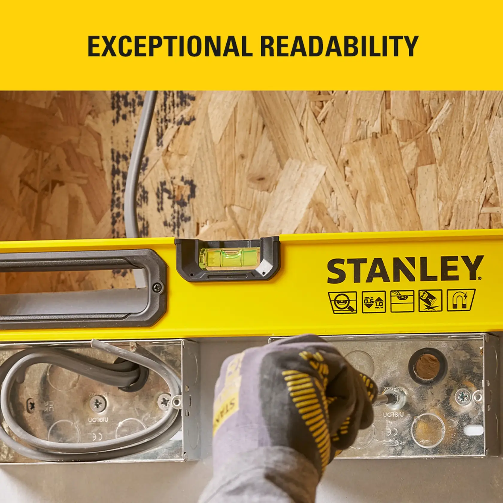 Photo of STANLEY STHT41724-0 spirit level with handle, yellow body, clear vial, close-up on wooden background.