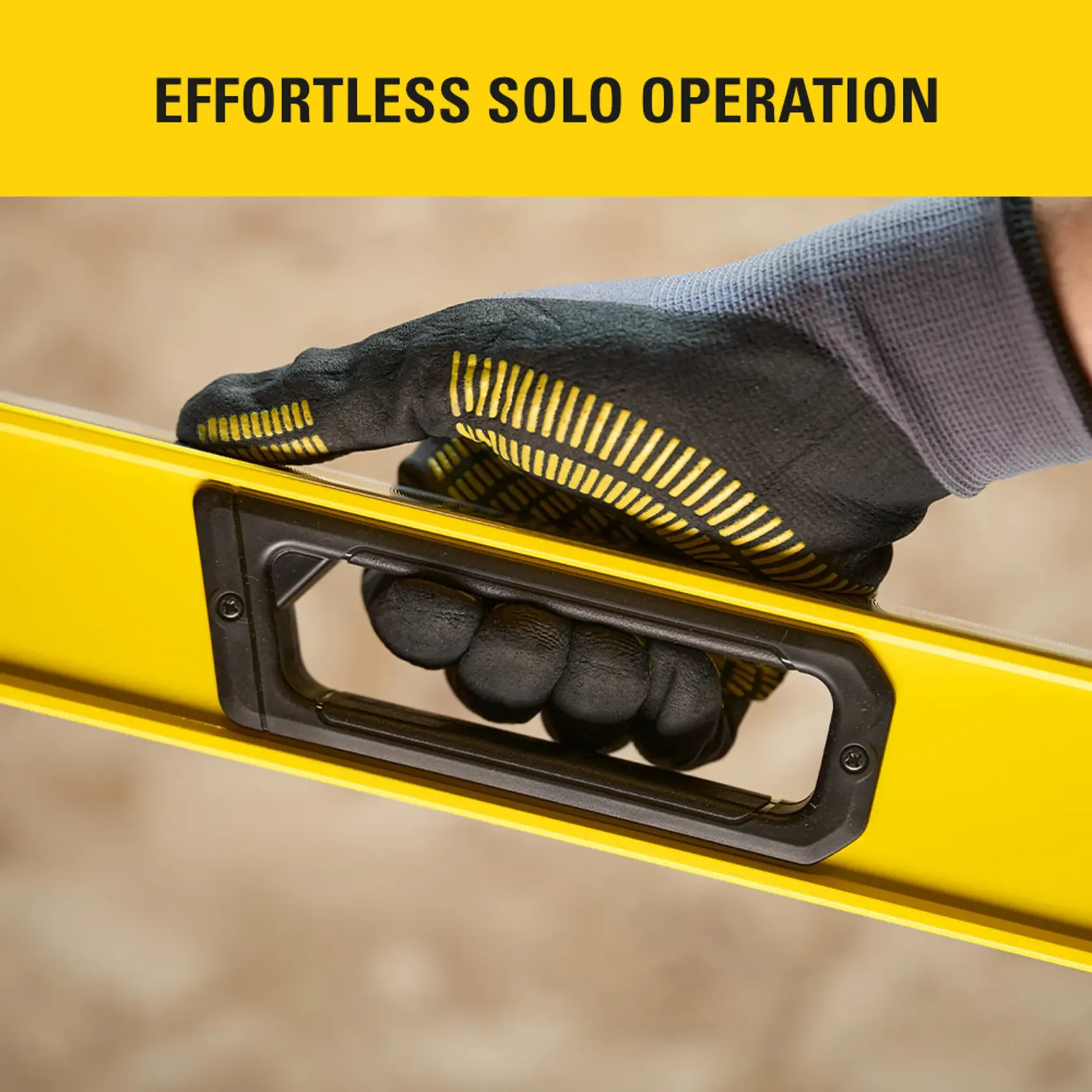 Photo of STANLEY STHT41748-0 level handle, yellow body, worker's gloved hand gripping for easy solo use.