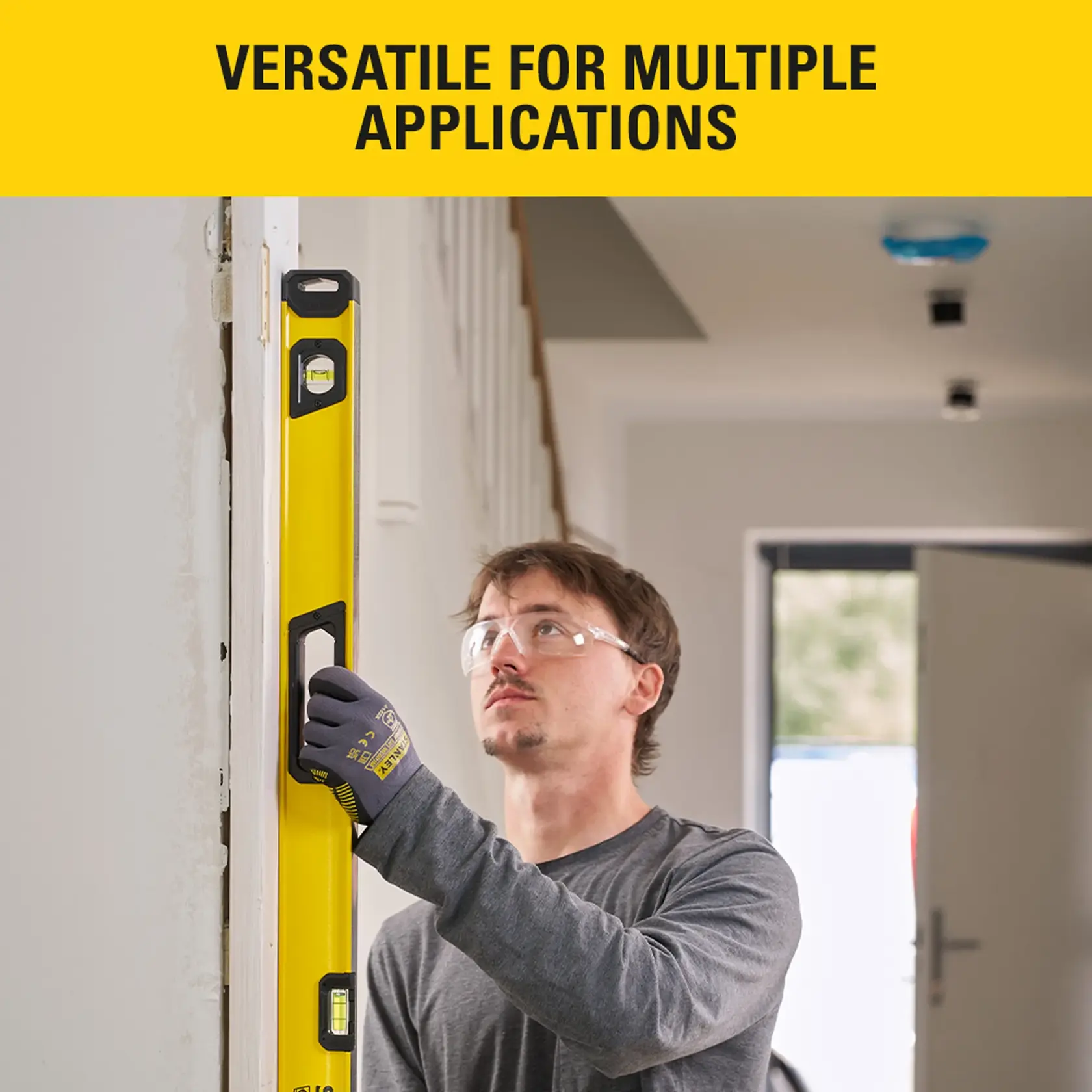 Photo of STANLEY STHT41748-0 graphics, man using yellow spirit level indoors for construction.