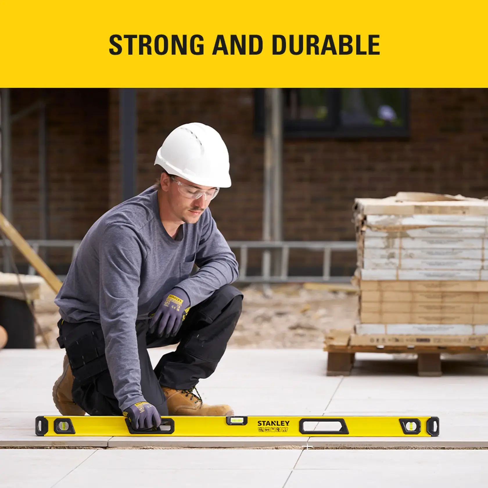 Photo of worker using STANLEY STHT41748-0 spirit level on floor tiles at a construction site.