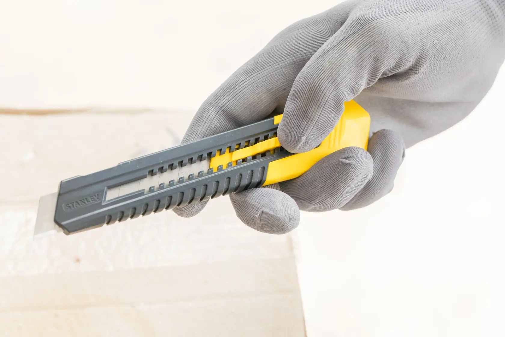 STANLEY 0-10-151 utility knife with yellow slider held by gloved hand, close-up side view.