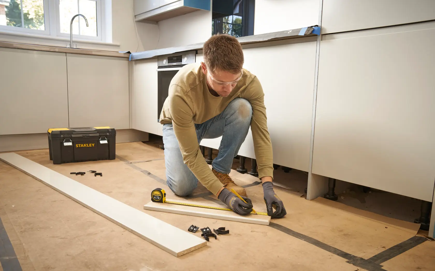 Photo of STANLEY 0-30-696 tape measure in use during kitchen installation, tool box visible in background.