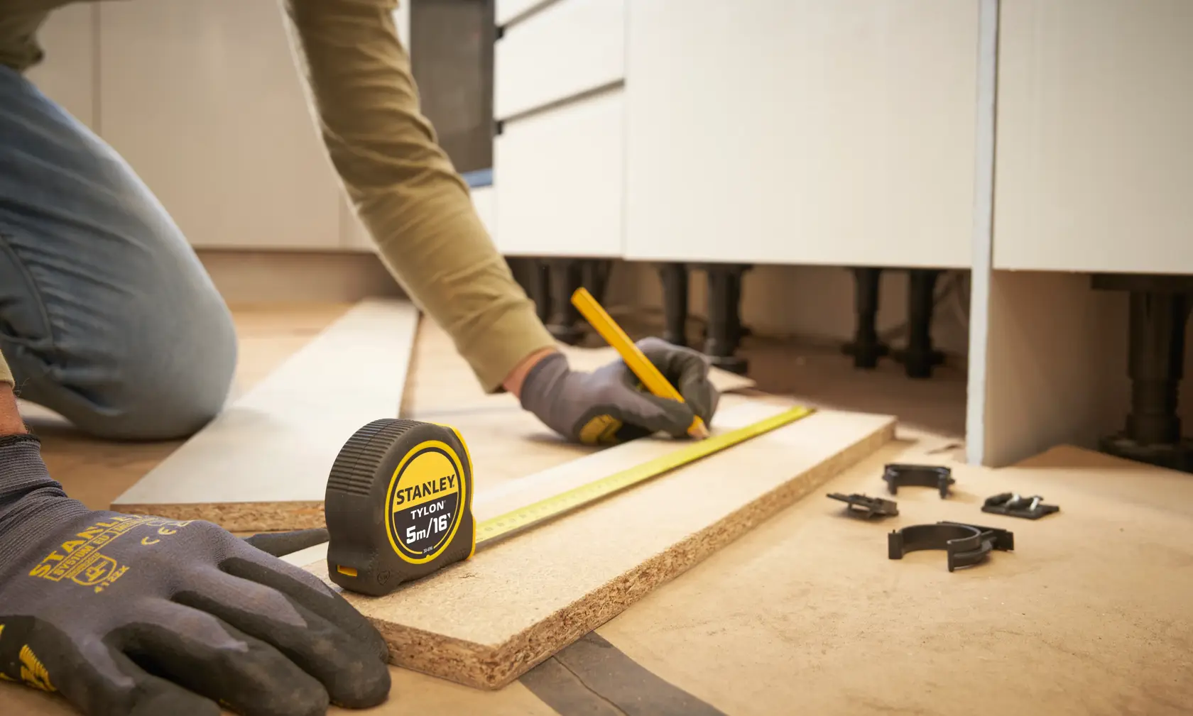 STANLEY 0-30-696 tape measure on wood board, person marking line with pencil, close-up, photography.