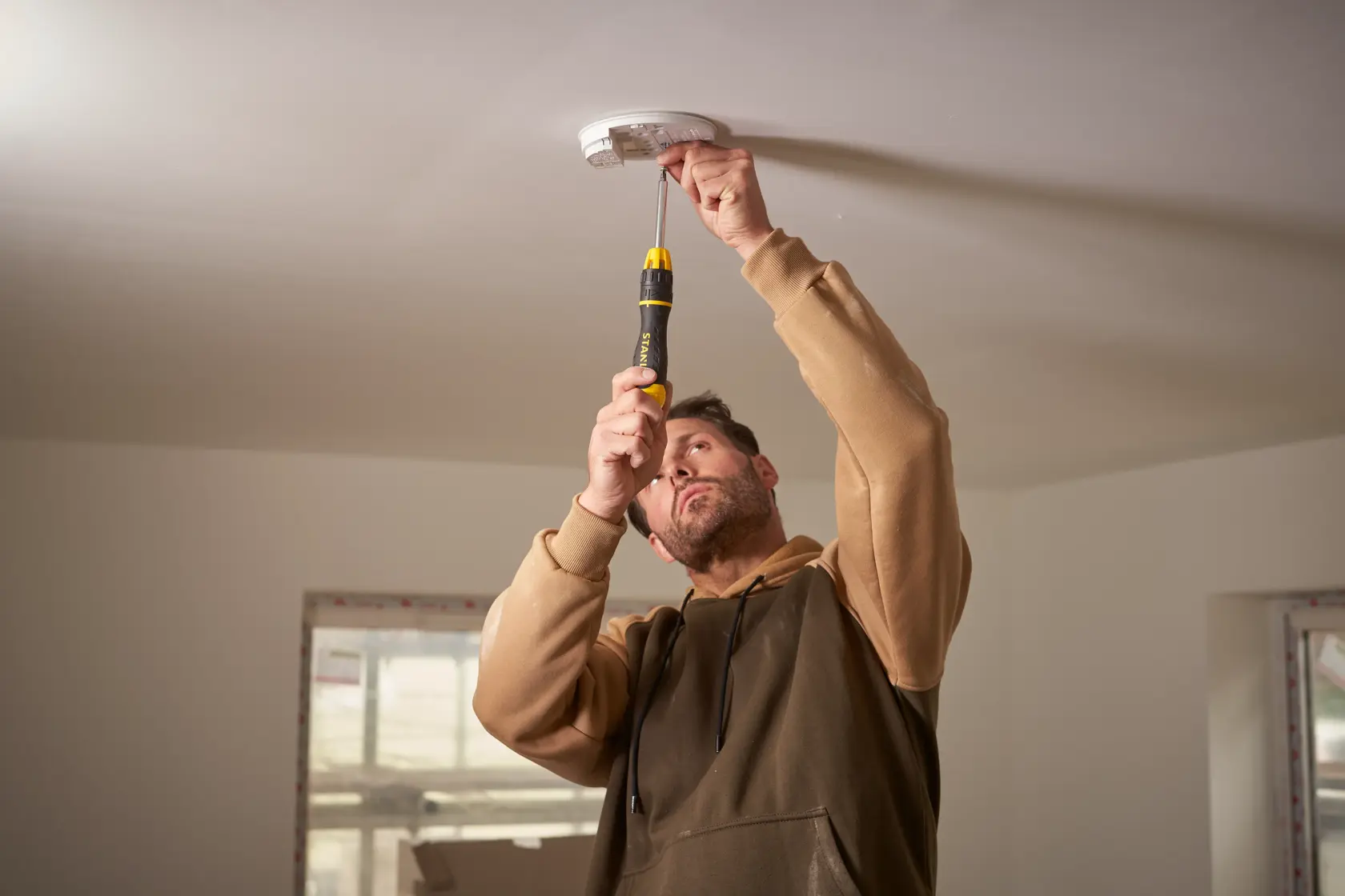 Photo of STANLEY 0-68-010 screwdriver used to install a smoke detector on a white ceiling.