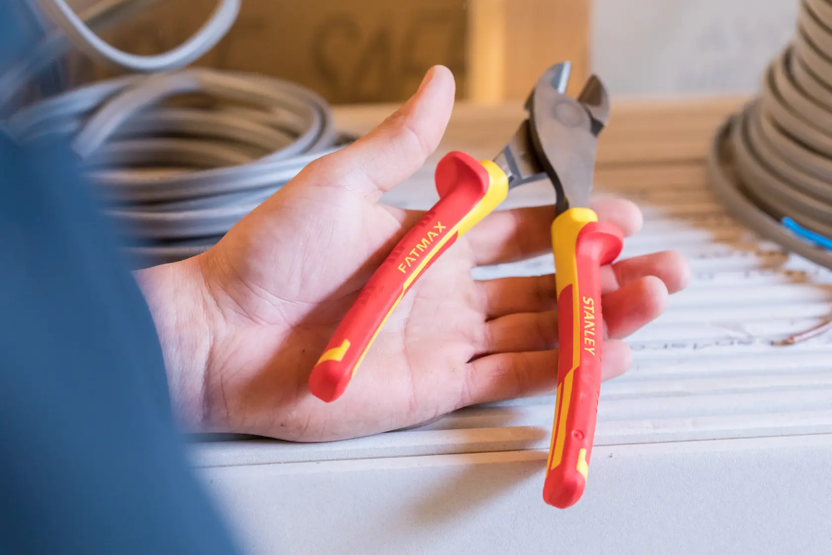 Stanley 0-84-004 insulated pliers with red-yellow handles, held in hand, close-up photo.