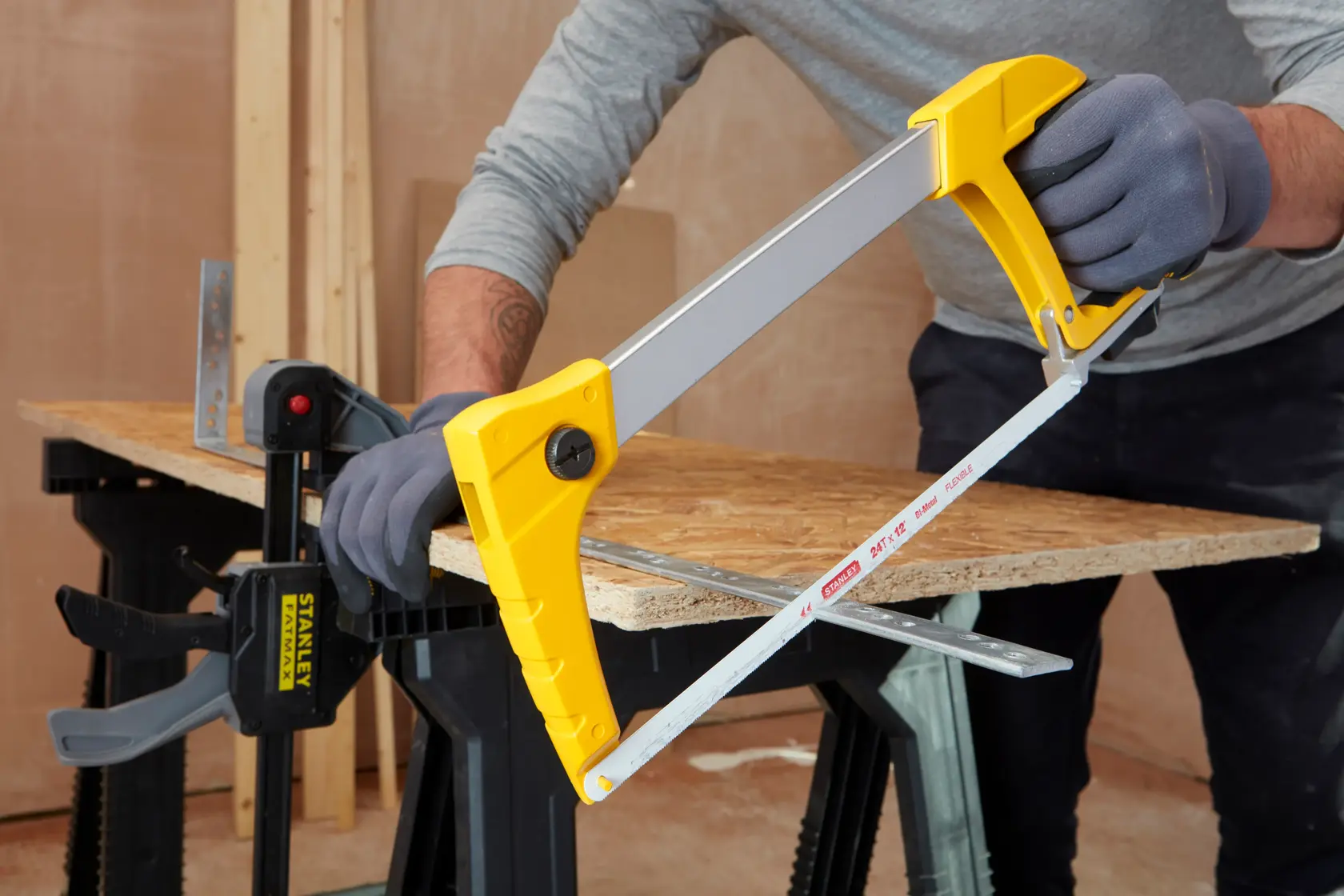 STANLEY 1-20-110 hacksaw with yellow handle cutting metal on workbench, photography of tool in use.