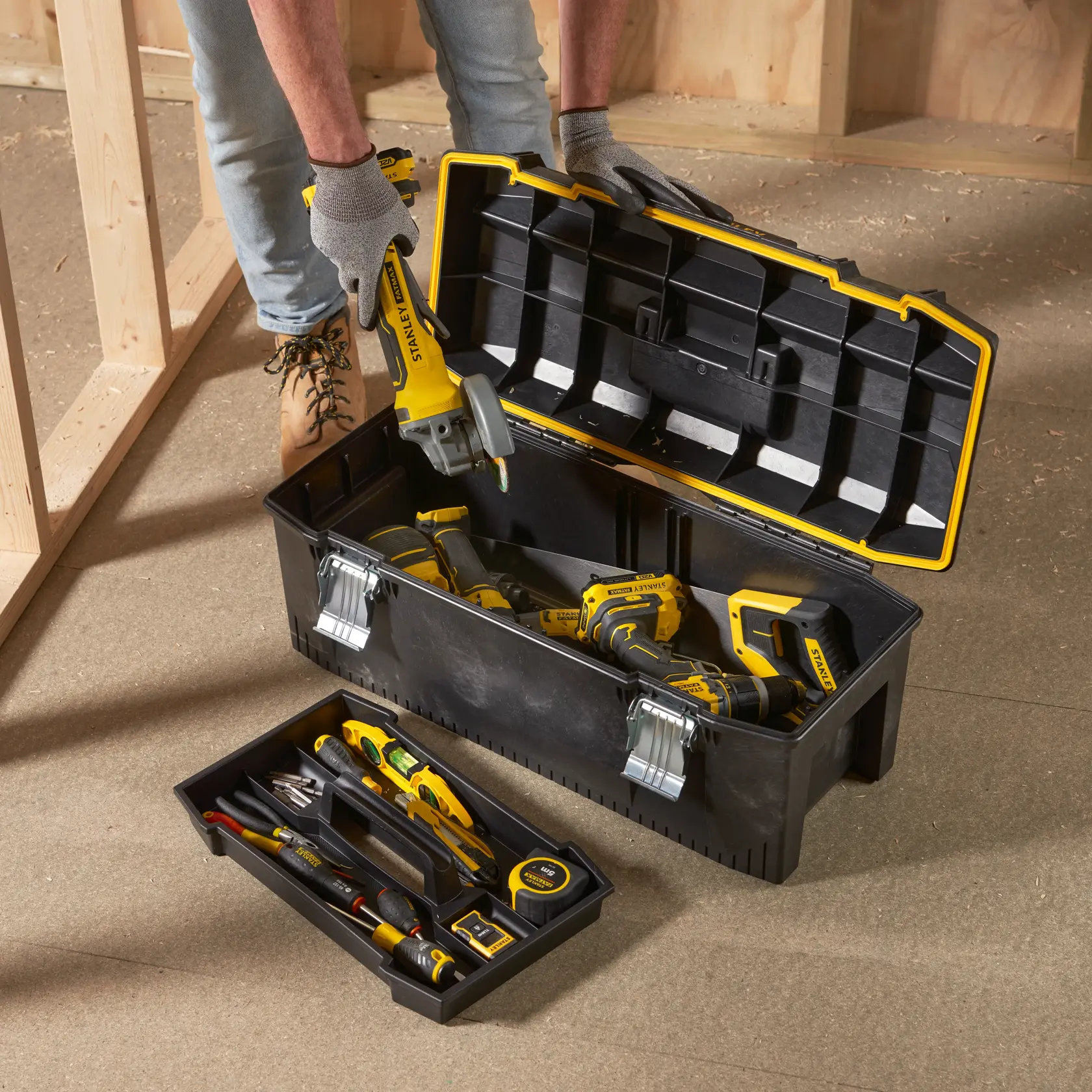 STANLEY 1-93-935 toolbox with hand tools and power tools, open on a workshop floor, photography angle from above.