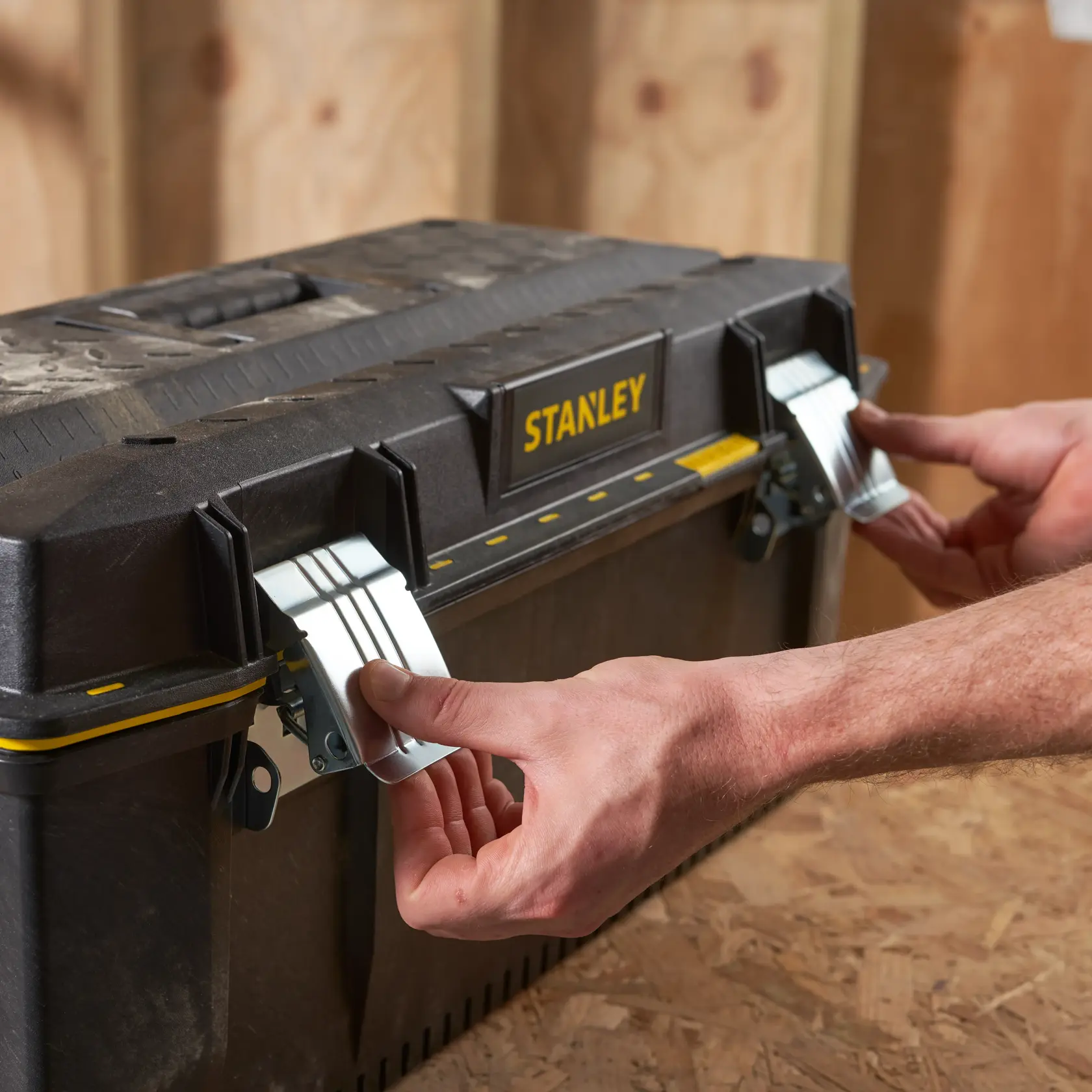 Photo of STANLEY 1-93-935 toolbox with metal latches being opened, black and yellow design.
