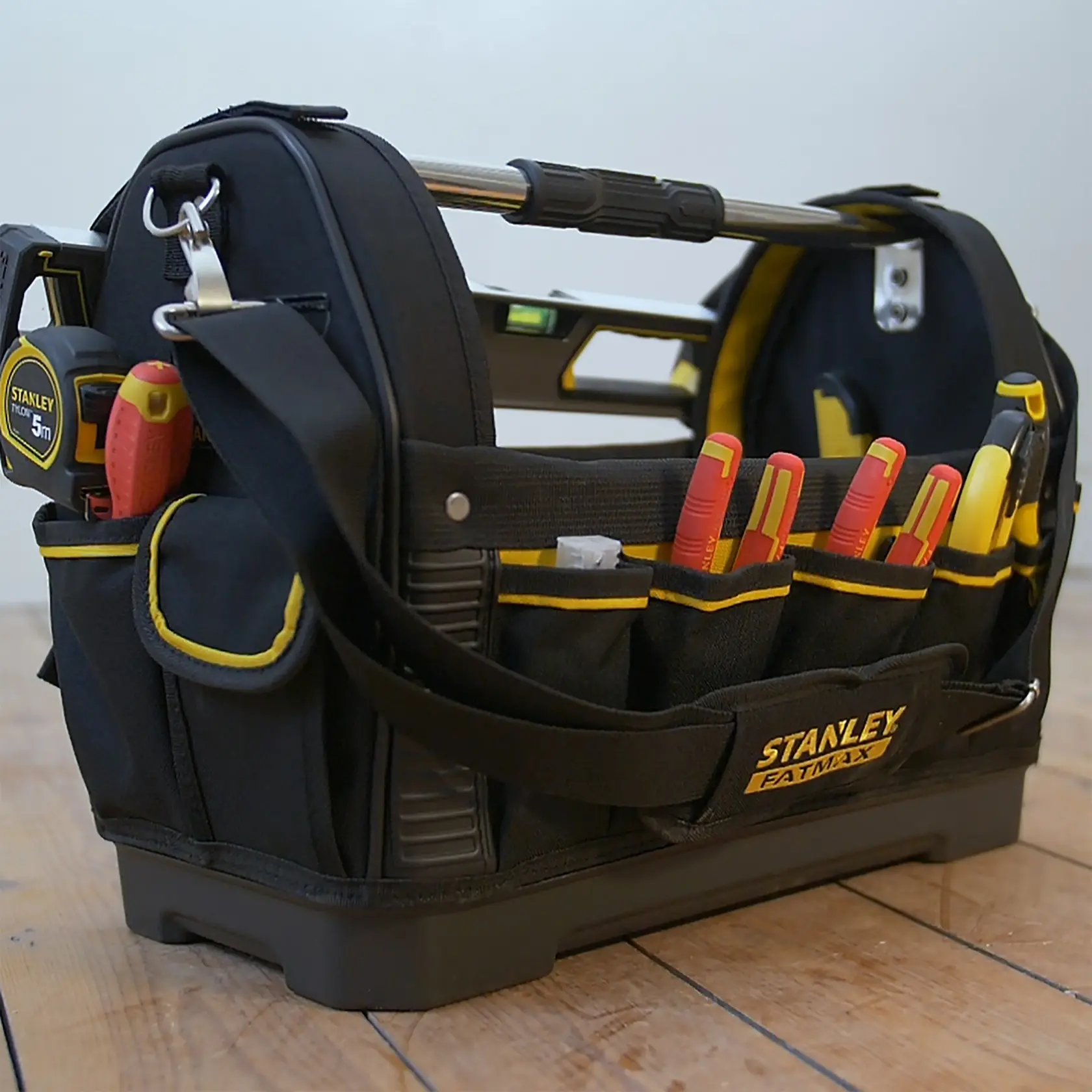 STANLEY 1-93-951 FATMAX tool bag with tools, side angle, black and yellow on wooden floor.