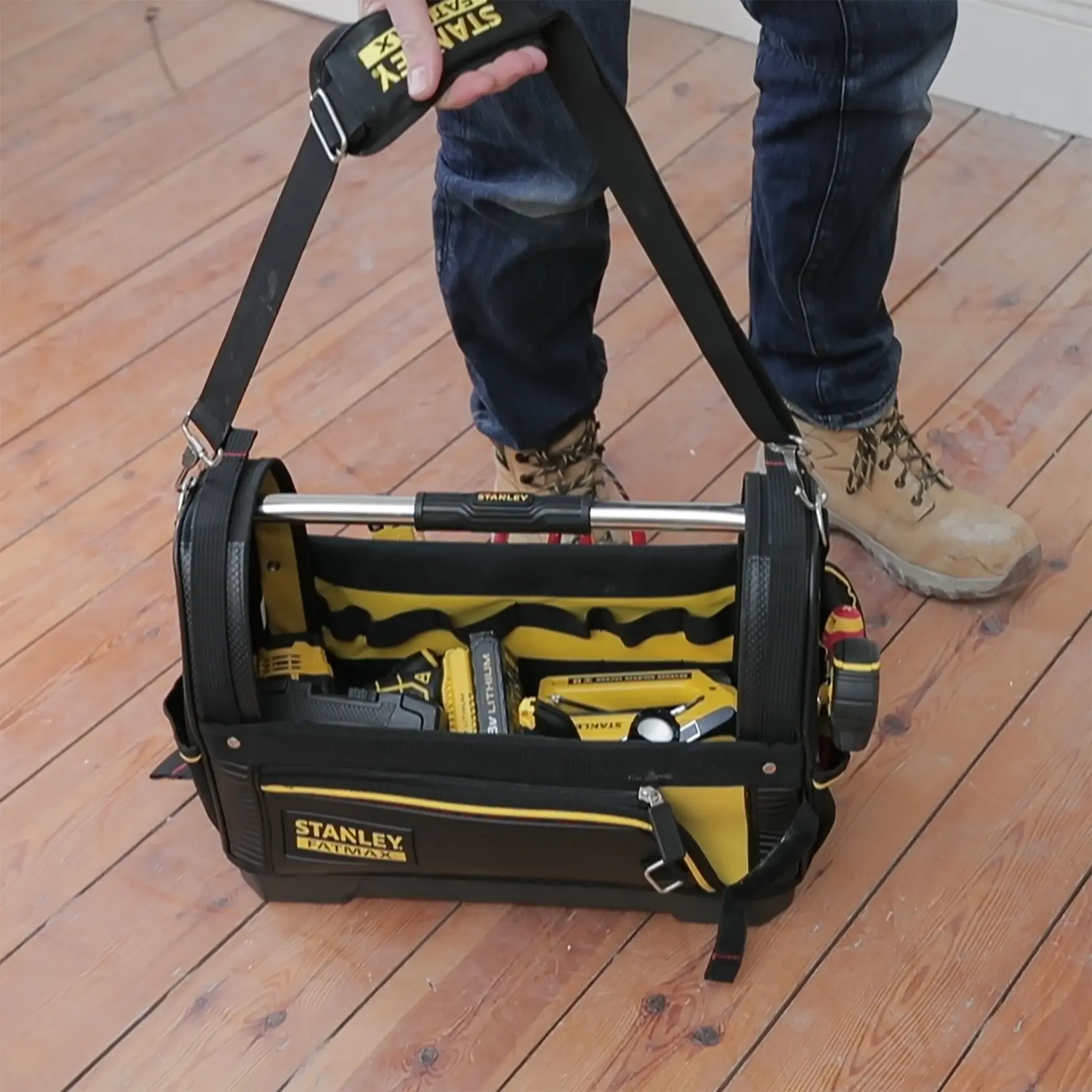 STANLEY 1-93-951 tool bag with shoulder strap filled with tools, photographed on wooden floor.