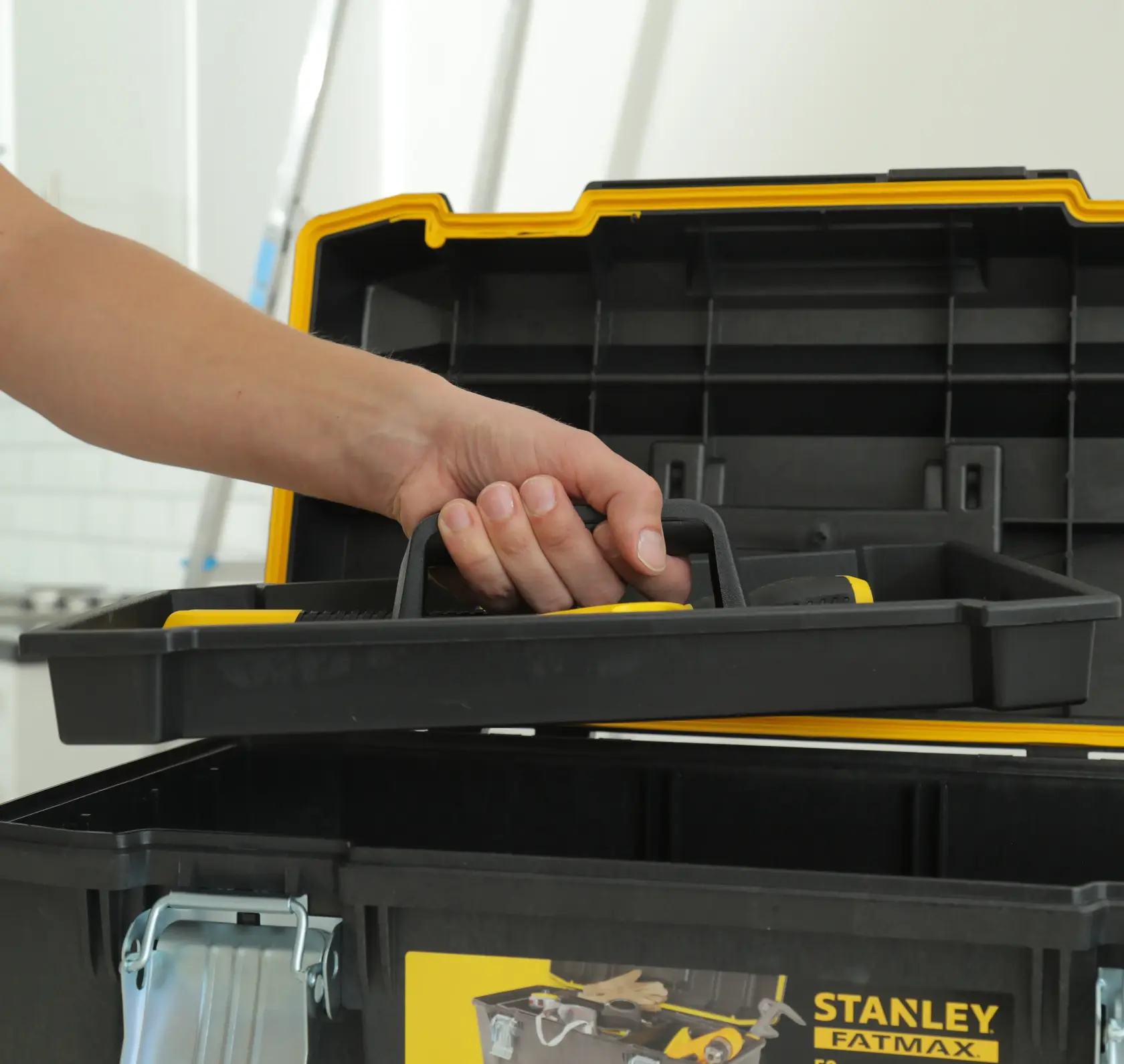 STANLEY 1-94-749 toolbox interior tray being lifted by hand, black and yellow plastic, photography side angle.