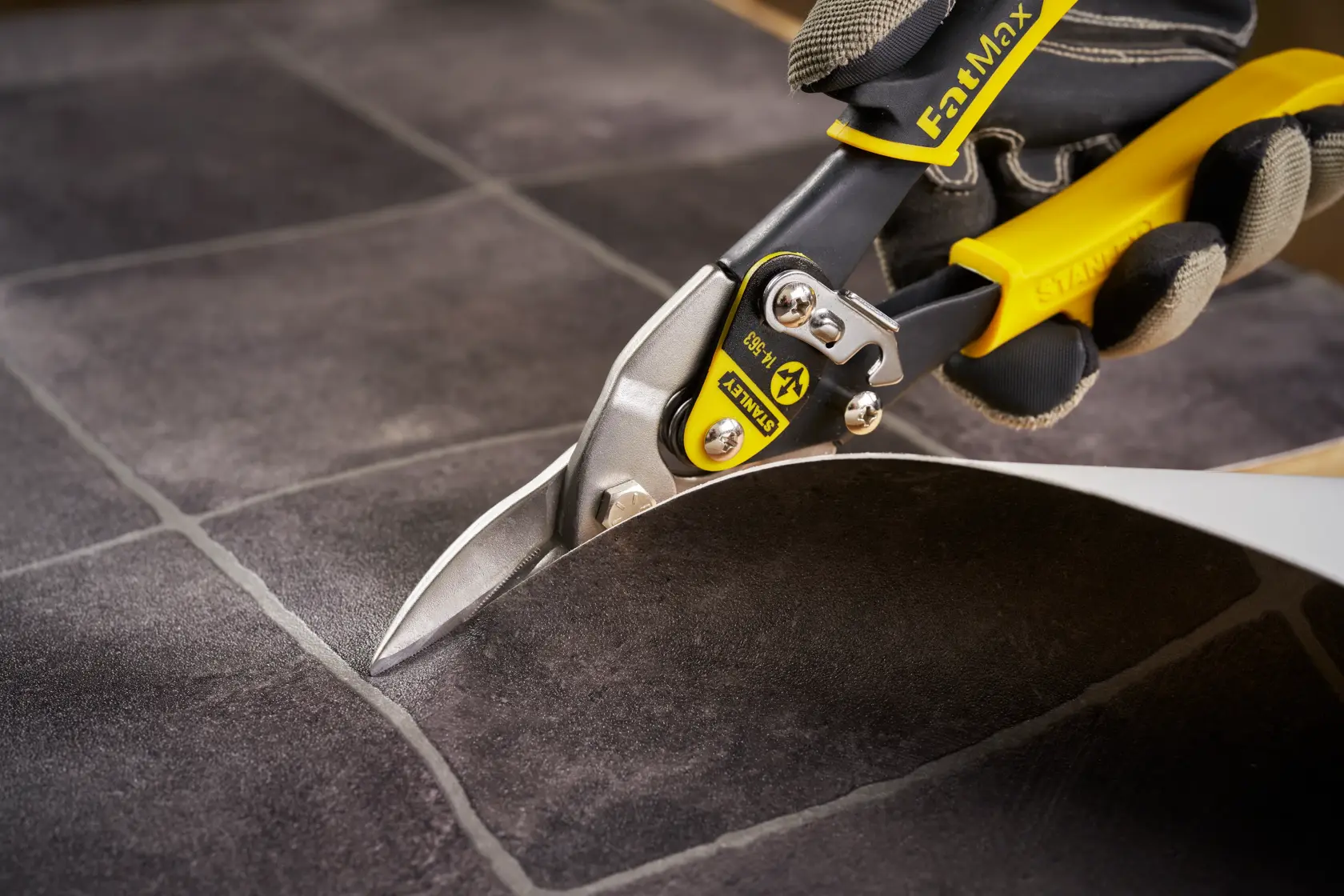 Photo of STANLEY 14-564 aviation snips cutting a sheet, close-up of blades and yellow handle in use.