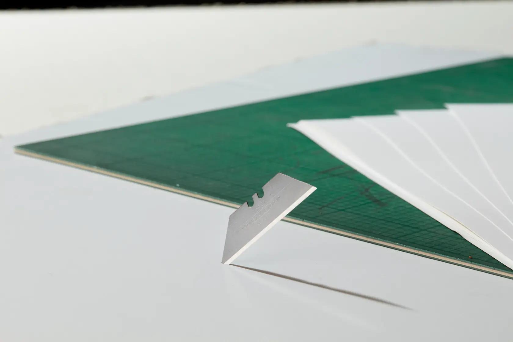 STANLEY 2-11-921 razor blade on white surface with green cutting mat and white sheets, side angle.