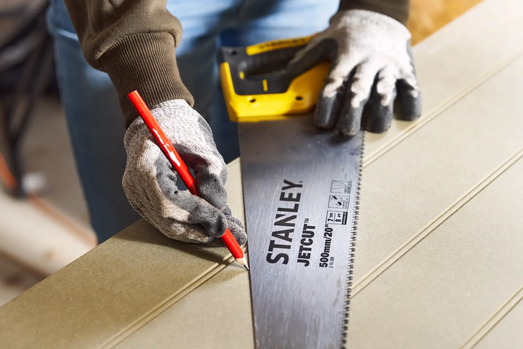 STANLEY 2-15-288 handsaw used to mark wood with pencil, close-up view showing handle and blade details.