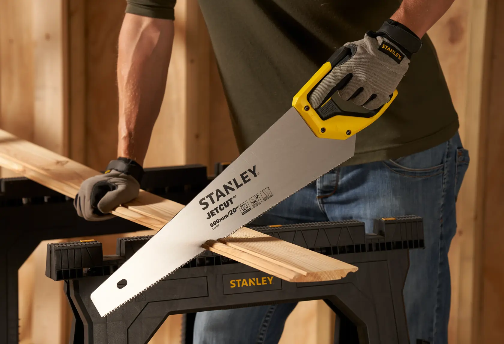 Photo of STANLEY 2-15-599 hand saw cutting wood on sawhorse, closeup of blade and yellow handle.