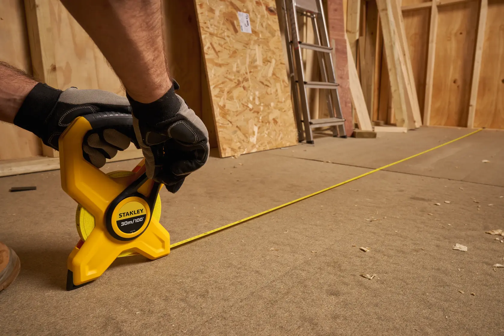 Photo of a STANLEY 34-791 open reel long tape measure being used on a construction floor.