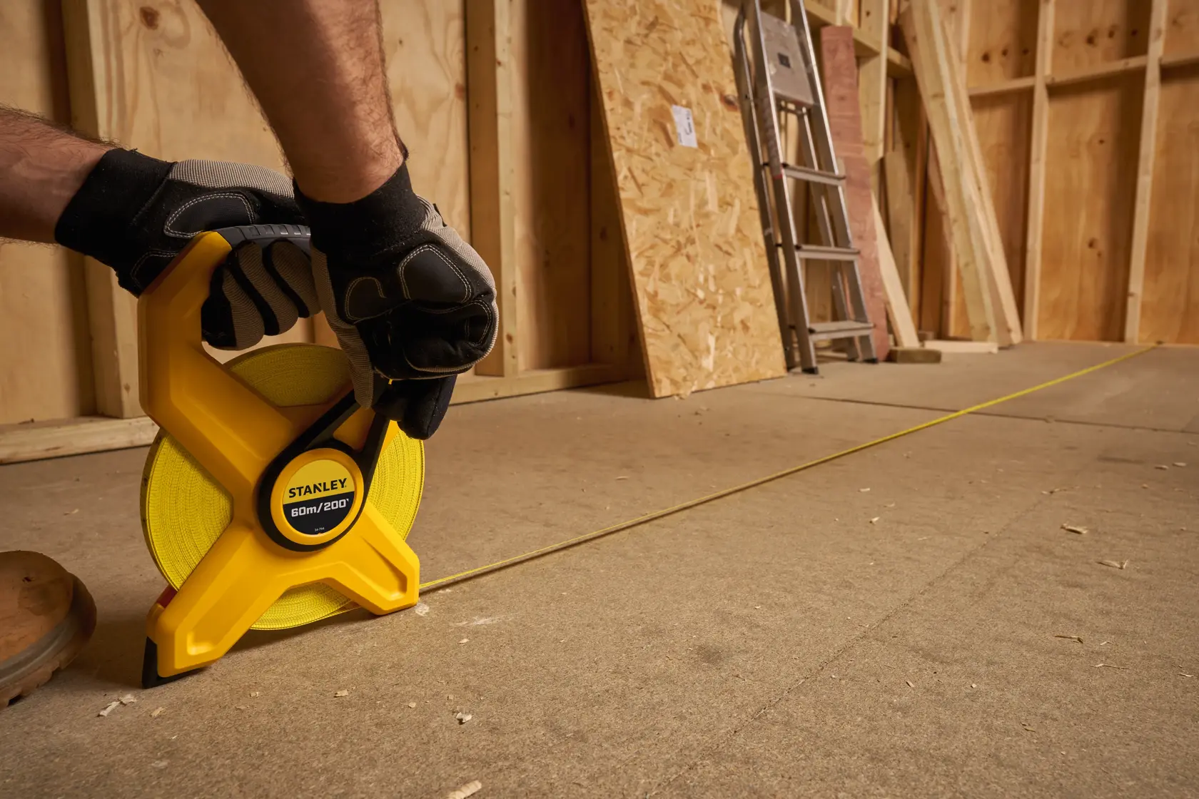 Photo of STANLEY 2-34-794 open reel yellow measuring tape in use on a construction floor.