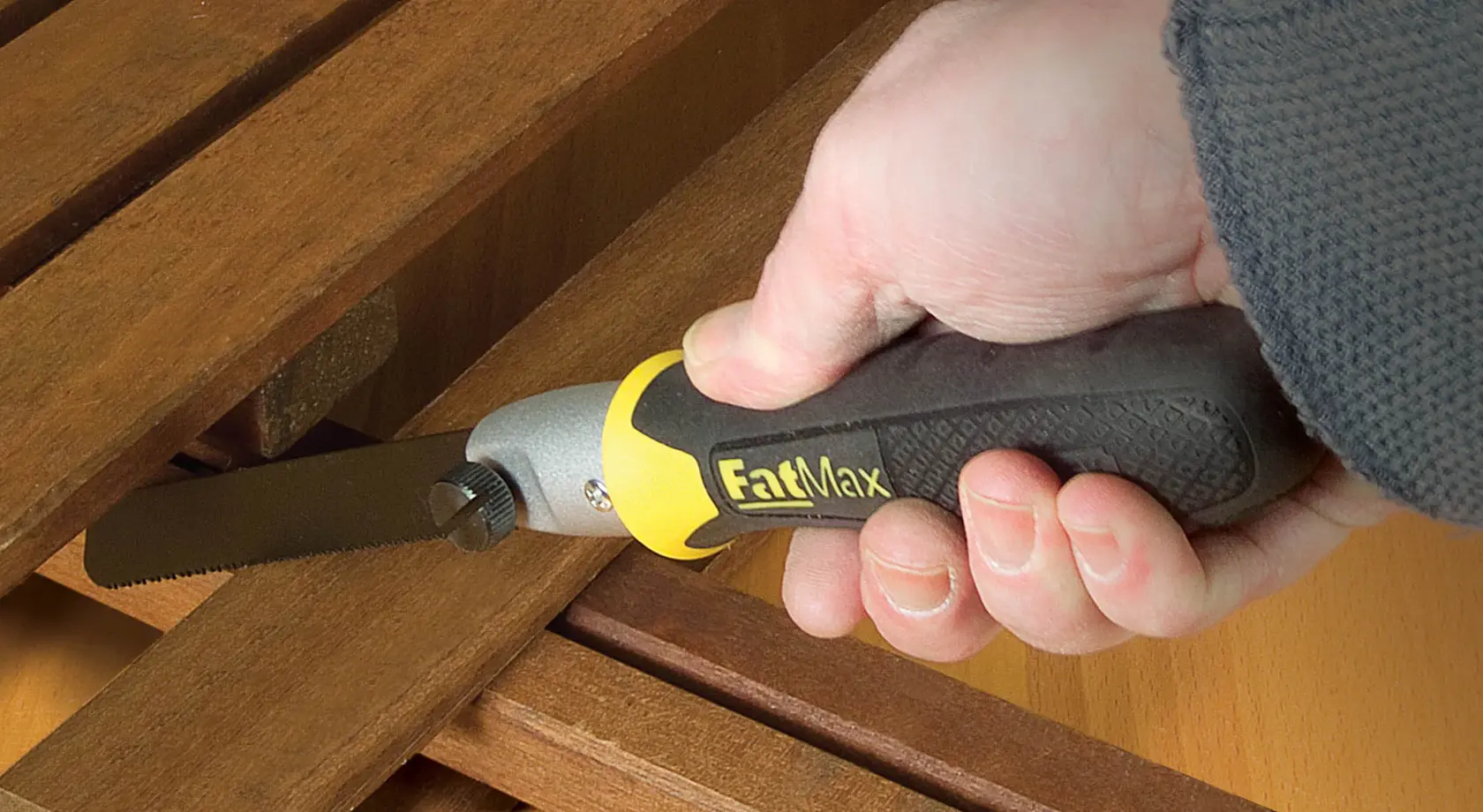 Stanley 20-220 FatMax hand saw in use cutting wood, close-up of ergonomic black and yellow handle.