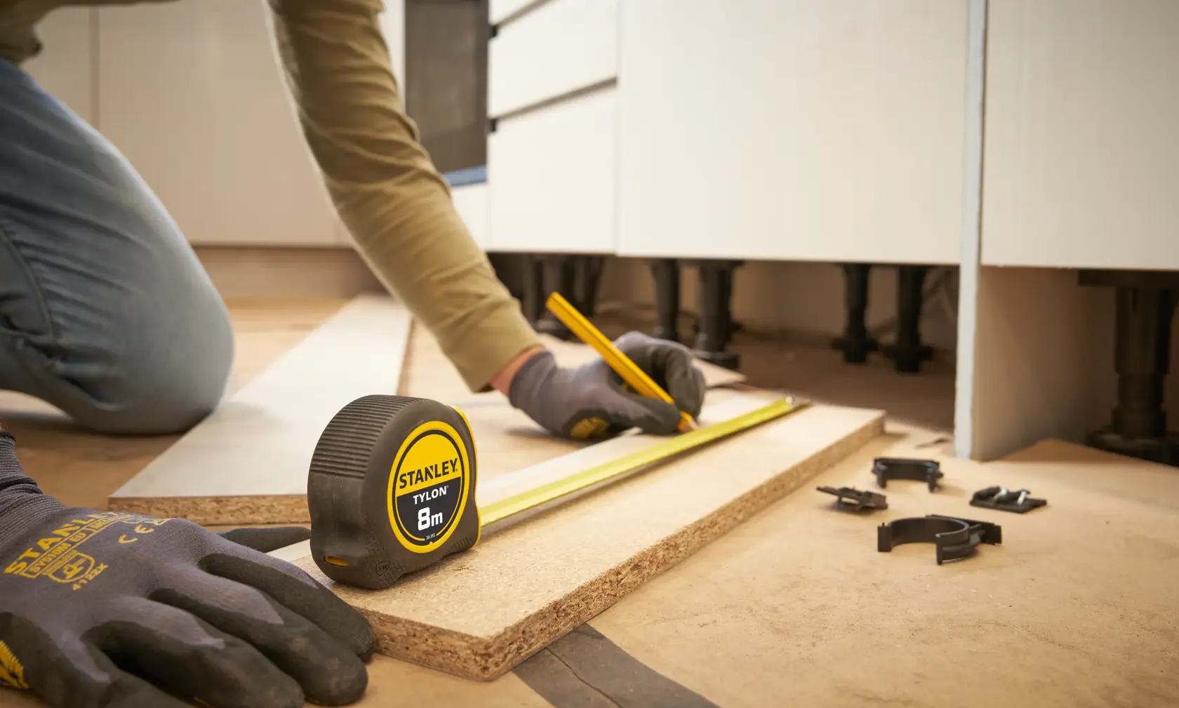 STANLEY 30-393 tape measure used for marking wood, close up, person wearing gloves.