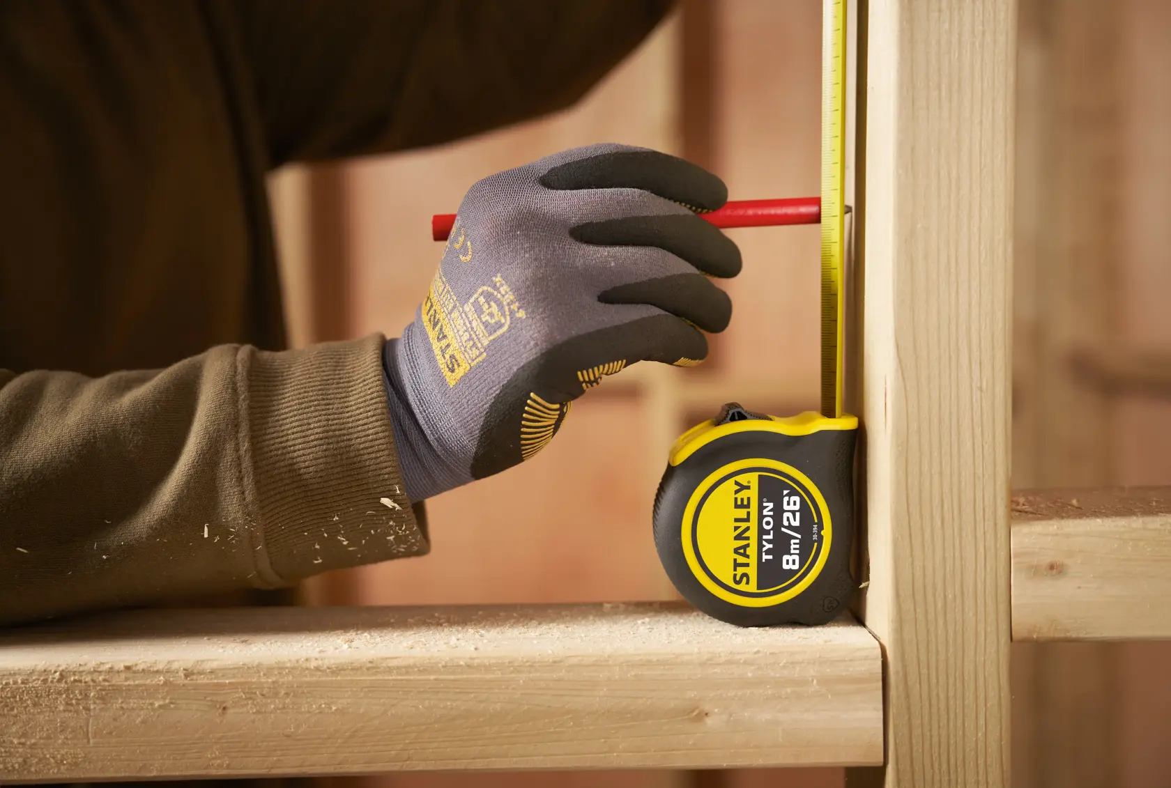 STANLEY 30-394 tape measure in use, worker with gloves marking wood, shown in workshop setting.