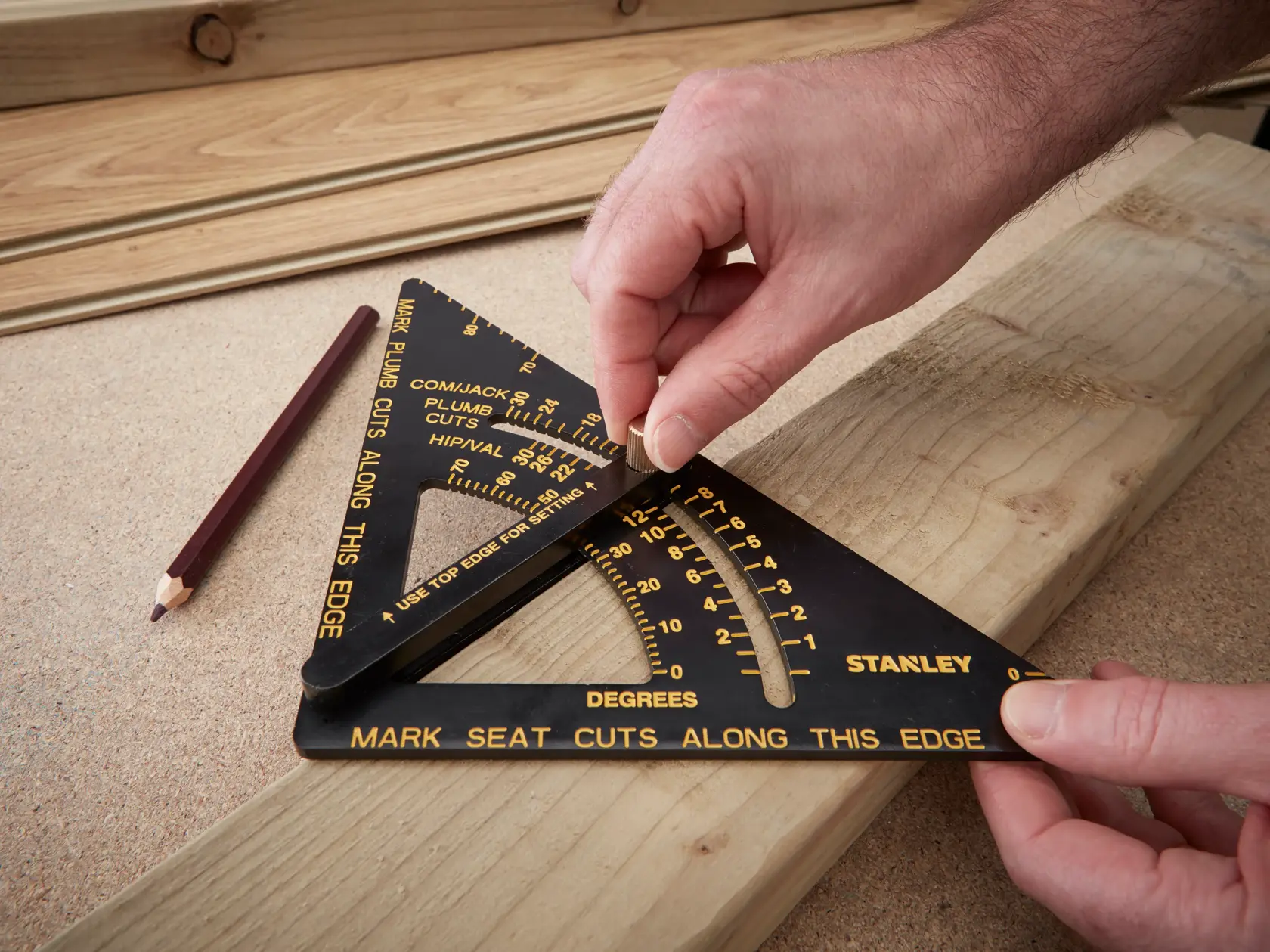 STANLEY 46-053 photography of black speed square with yellow markings on wood, hands setting angle, pencil nearby.