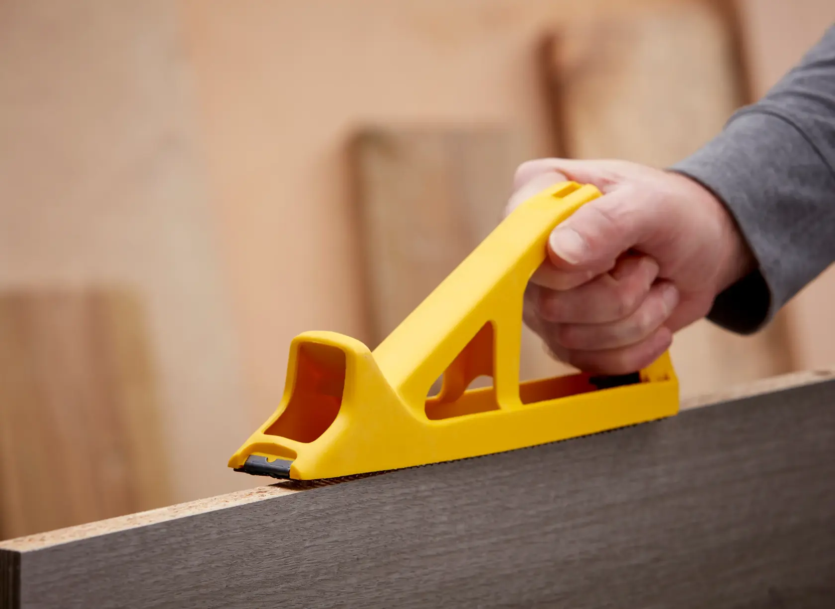 STANLEY 5-21-103 hand rasp tool in yellow, shown smoothing wood surface in close-up photography.