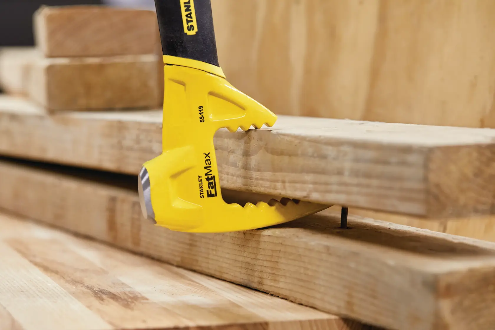 STANLEY 55-119 FatMax demolition tool prying wood boards with claw in construction setting.
