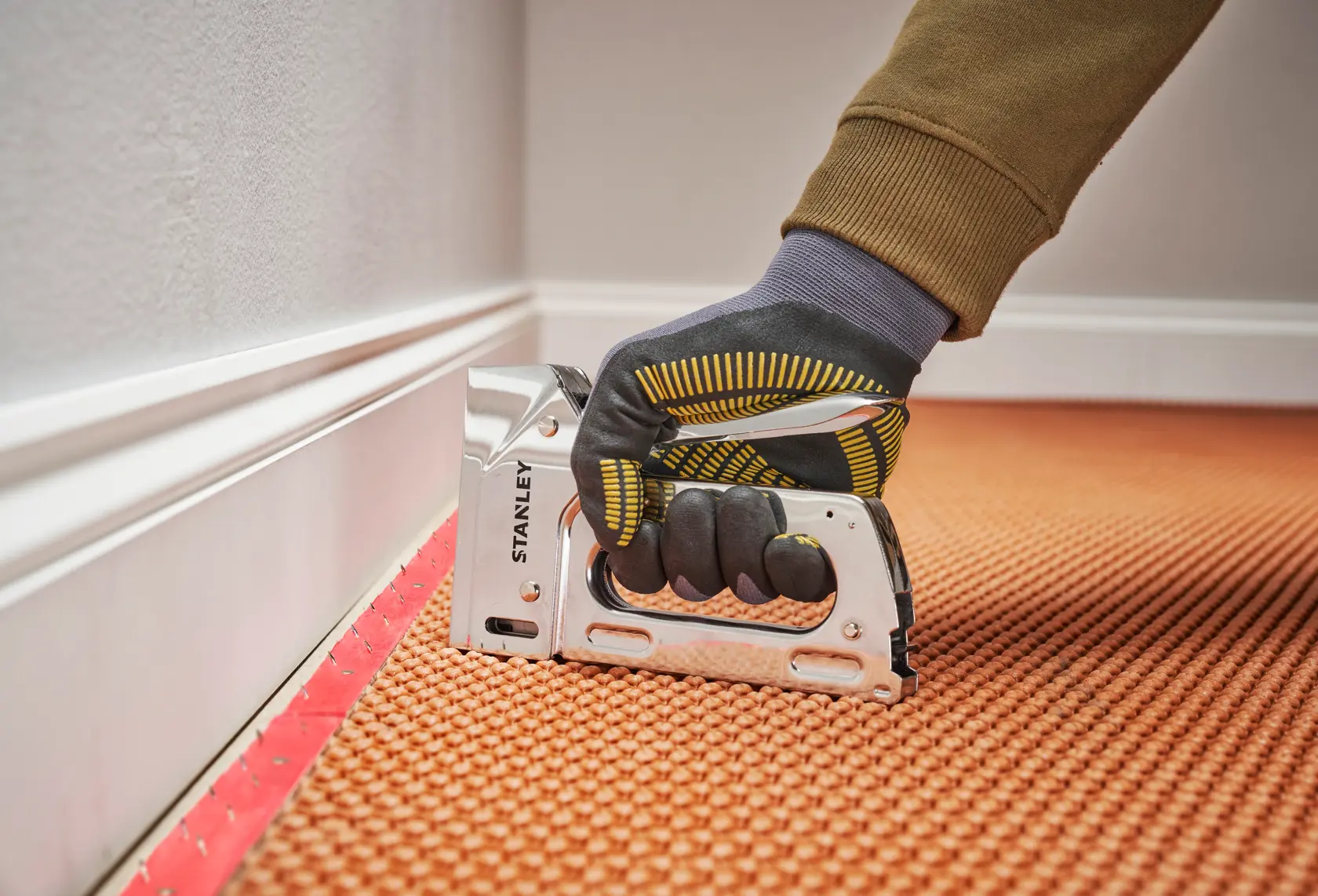 Photo of STANLEY 6-TR110 manual staple gun used to fasten carpet, close-up, side angle.