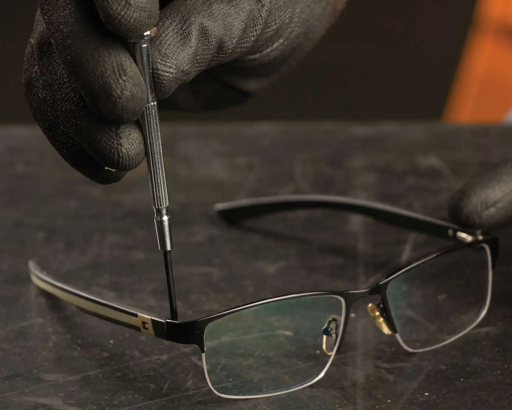 Photo of STANLEY 66-039 precision screwdriver being used to repair eyeglasses on a dark surface.