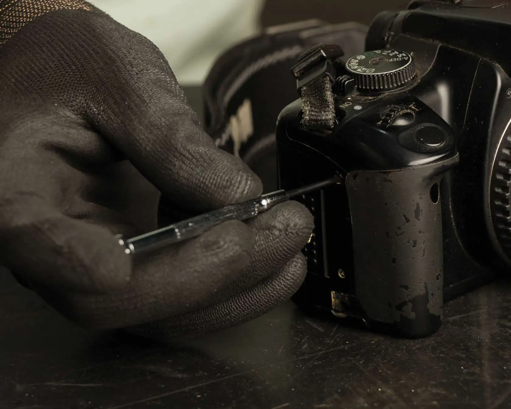 STANLEY 66-039 screwdriver used to repair a black camera, close-up photography of hand wearing black glove.