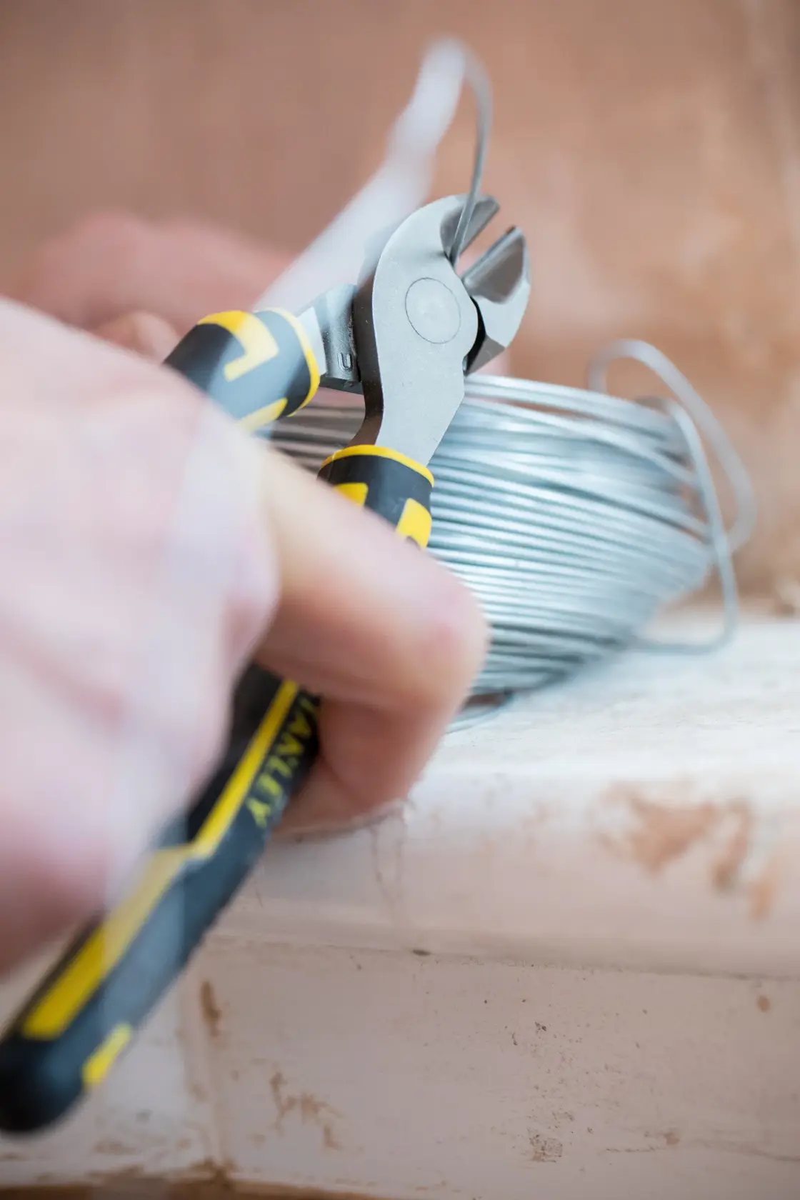 Photo of STANLEY 89-859 diagonal cutting pliers with black and yellow handles held in a hand, side view.