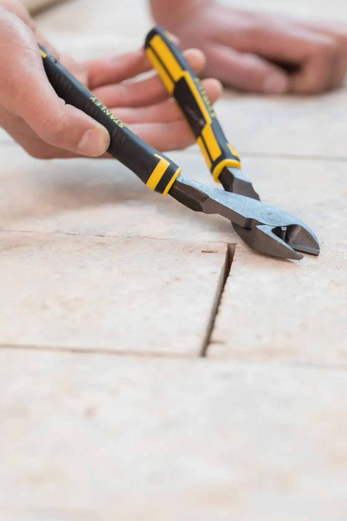 STANLEY 89-861 diagonal cutting pliers with black and yellow handles in use on tile surface, close-up.