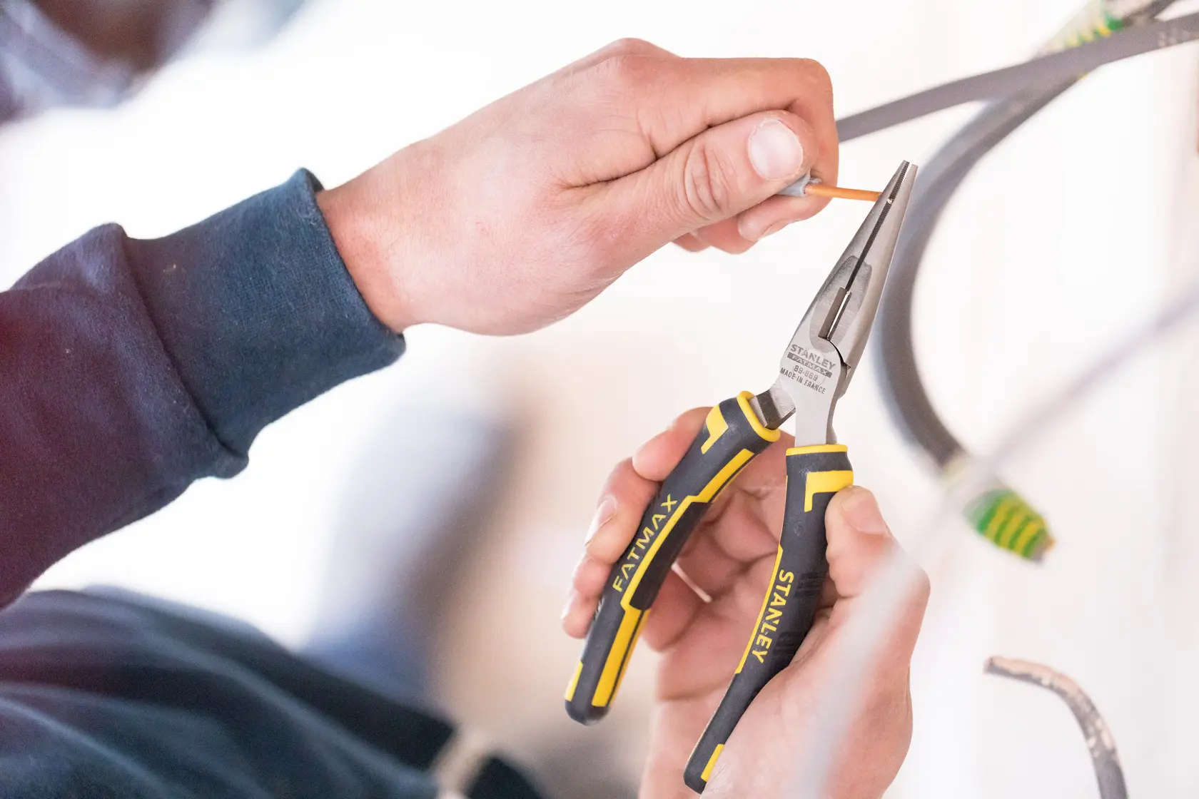 Photo of STANLEY 89-869 long nose pliers with black and yellow handles in use, gripping wire.