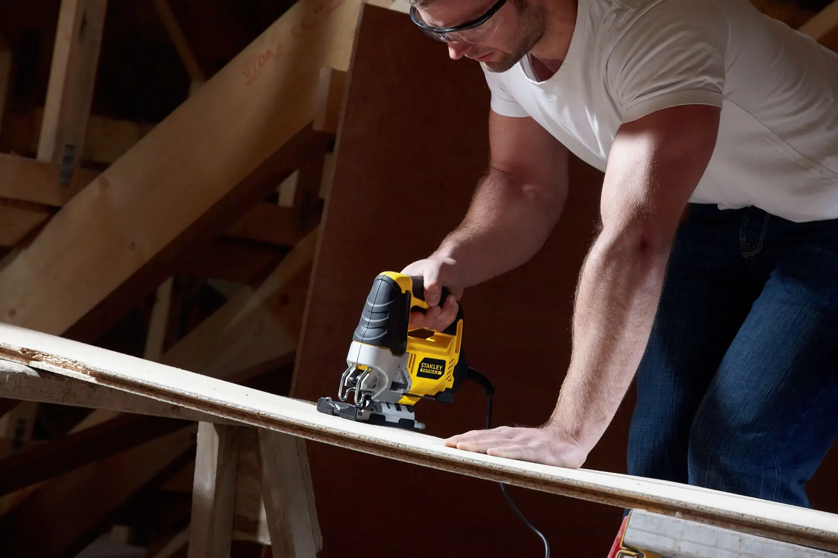 STANLEY FME340K jigsaw tool cutting wood plank, handheld, in workshop setting.