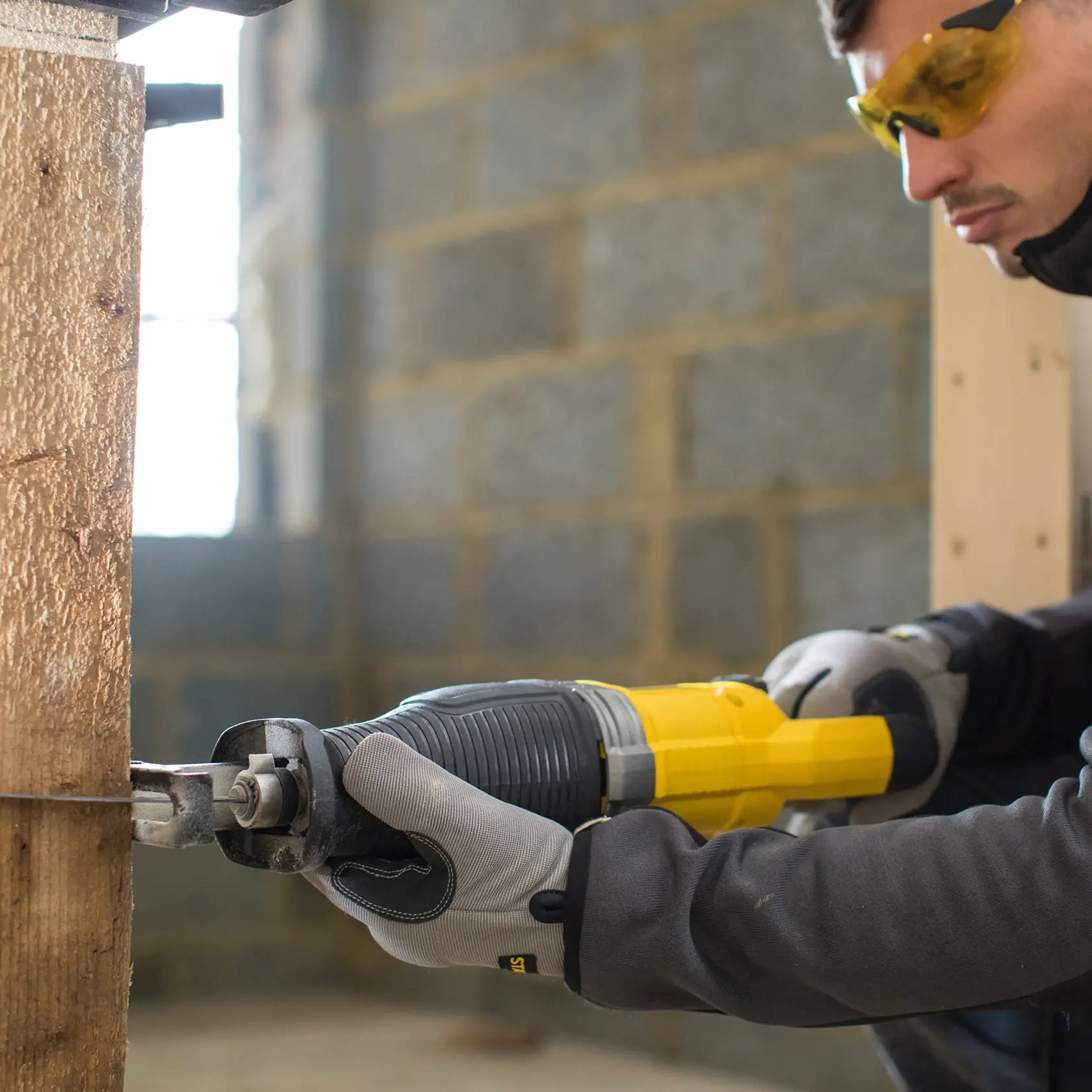 STANLEY FME360 reciprocating saw in use cutting wood, close-up view, user wearing gloves and safety glasses.