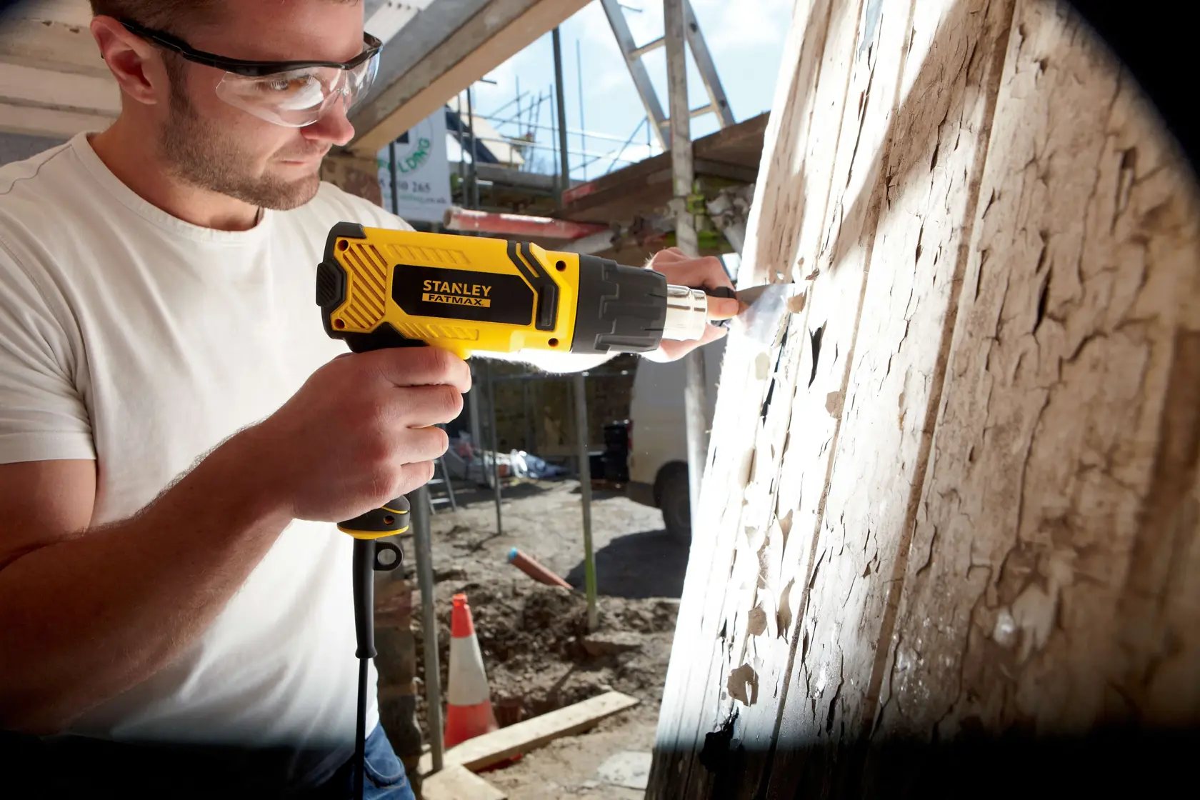 Photo of STANLEY FME670K heat gun used for paint removal on wood surface at construction site.