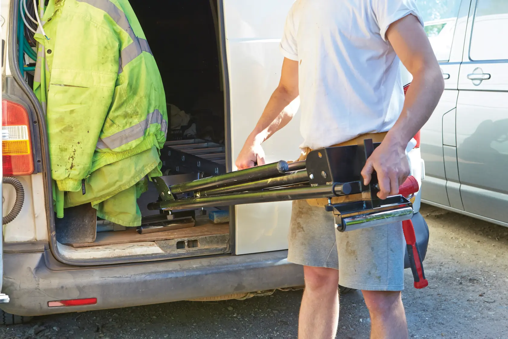 STANLEY FME790-XE tripod saw stand held by worker beside van, outdoor setting, product in use.