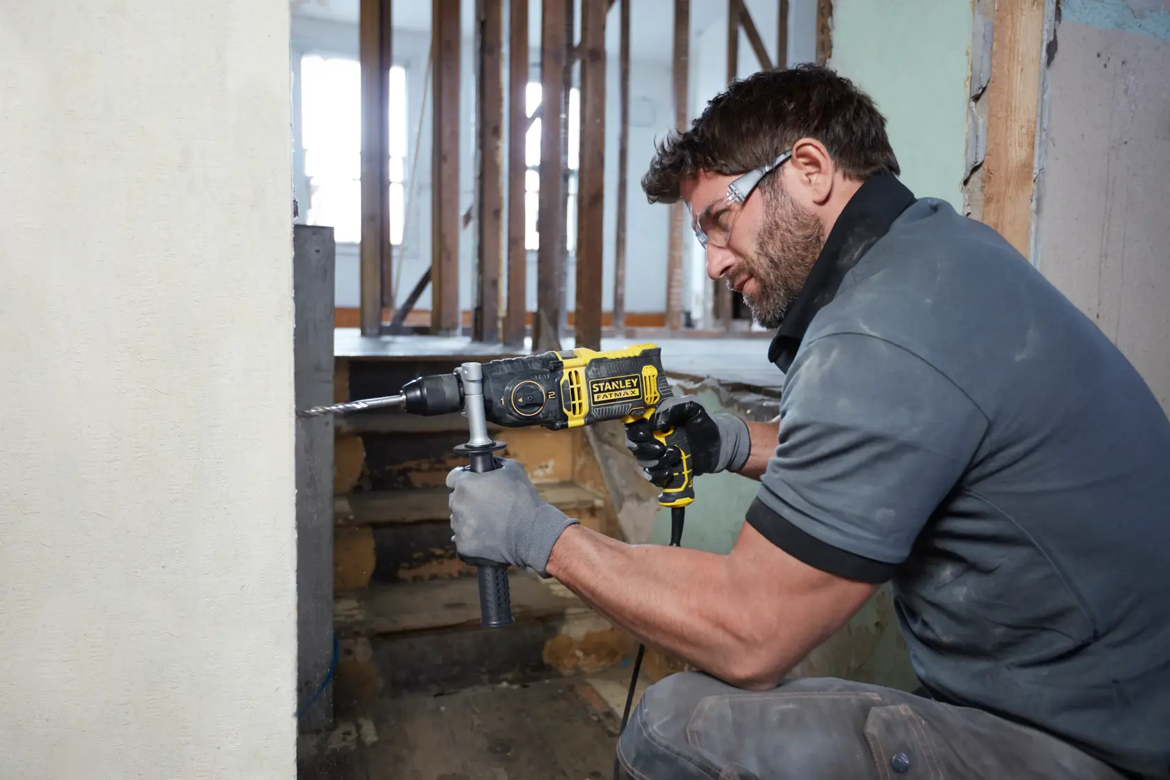 Photo of STANLEY FMEH1100K hammer drill in use, yellow and black, drilling into a wall during renovation.