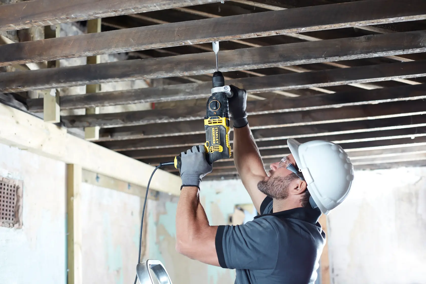 STANLEY FMEH1100K hammer drill used by worker for overhead drilling in construction site.