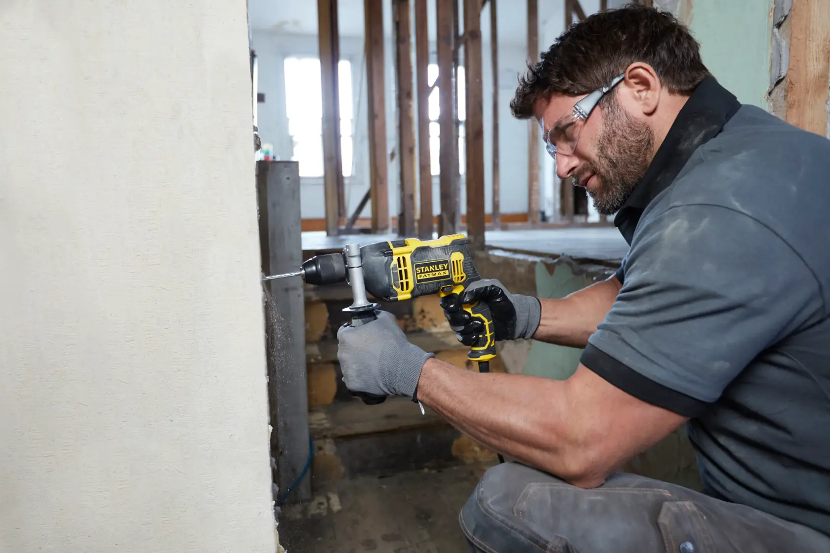 Photo of STANLEY FMEH750 hammer drill in use on a wall during construction renovation.